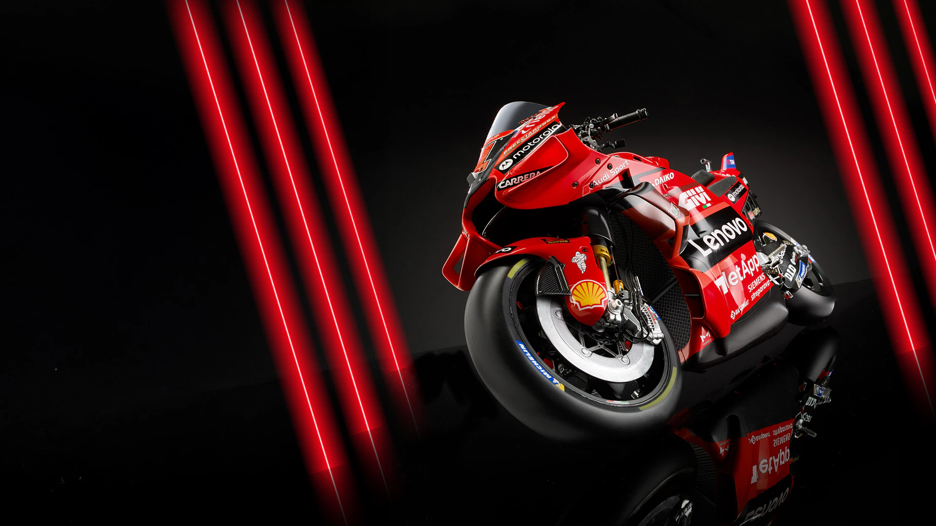 Εικόνα κόκκινης μοτοσυκλέτας Ducati σε μαύρο φόντο με κόκκινα νέον φώτα. Η εικόνα περιλαμβάνει το διαφημιστικό κείμενο: «Πρώτη αποστολή μόνο με 1 €».